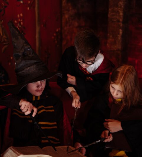 Students using their wands to make spell while reading a book